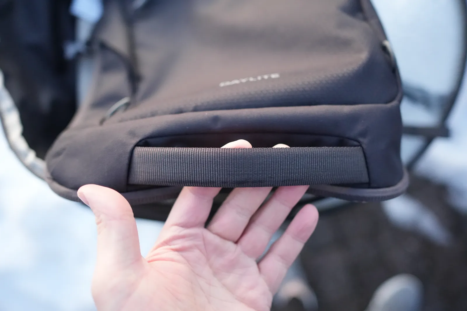Hand showing the bottom pocket area and luggage handle pass-through on the Osprey Daylite 35 with DAYLITE branding