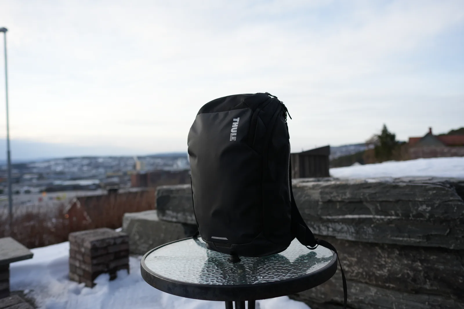 Thule Chasm 26L backpack front view on glass table with winter cityscape background